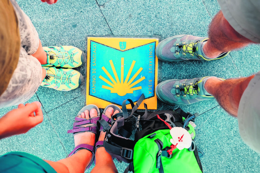 Three pairs piligrims feet on the start of the Camino de Santiago or “The Way of Saint James ” famous rout in Bilbao, Spain