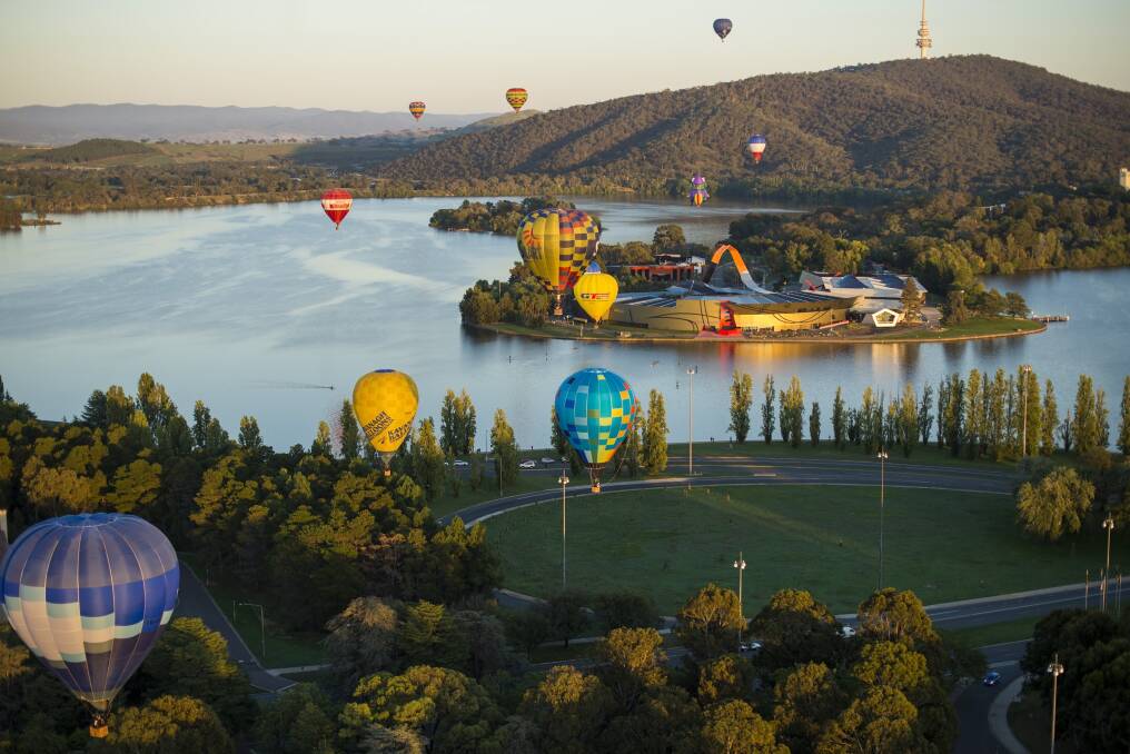 Hot air balloons drift by the National Museum of Australia.