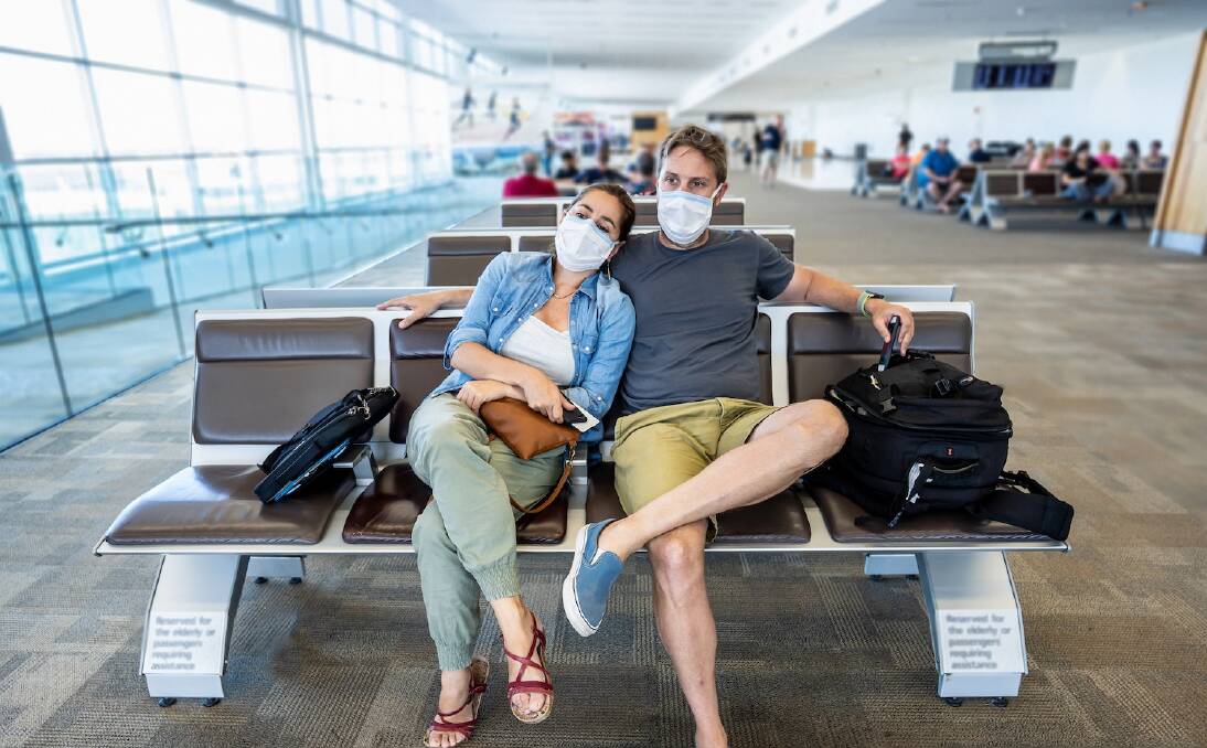 COVID-19 worldwide borders closures. Couple with face mask stuck in airport terminal after being denied entry to other countries. Passengers stranded in airport on his travel back to home country.